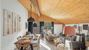 Een ruime woonkamer met een houten plafond, een eettafel gedekt voor vier personen en een gezellige zithoek.