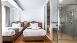 Une chambre d’hôtel avec deux lits, une douche en verre et vue sur la ville.