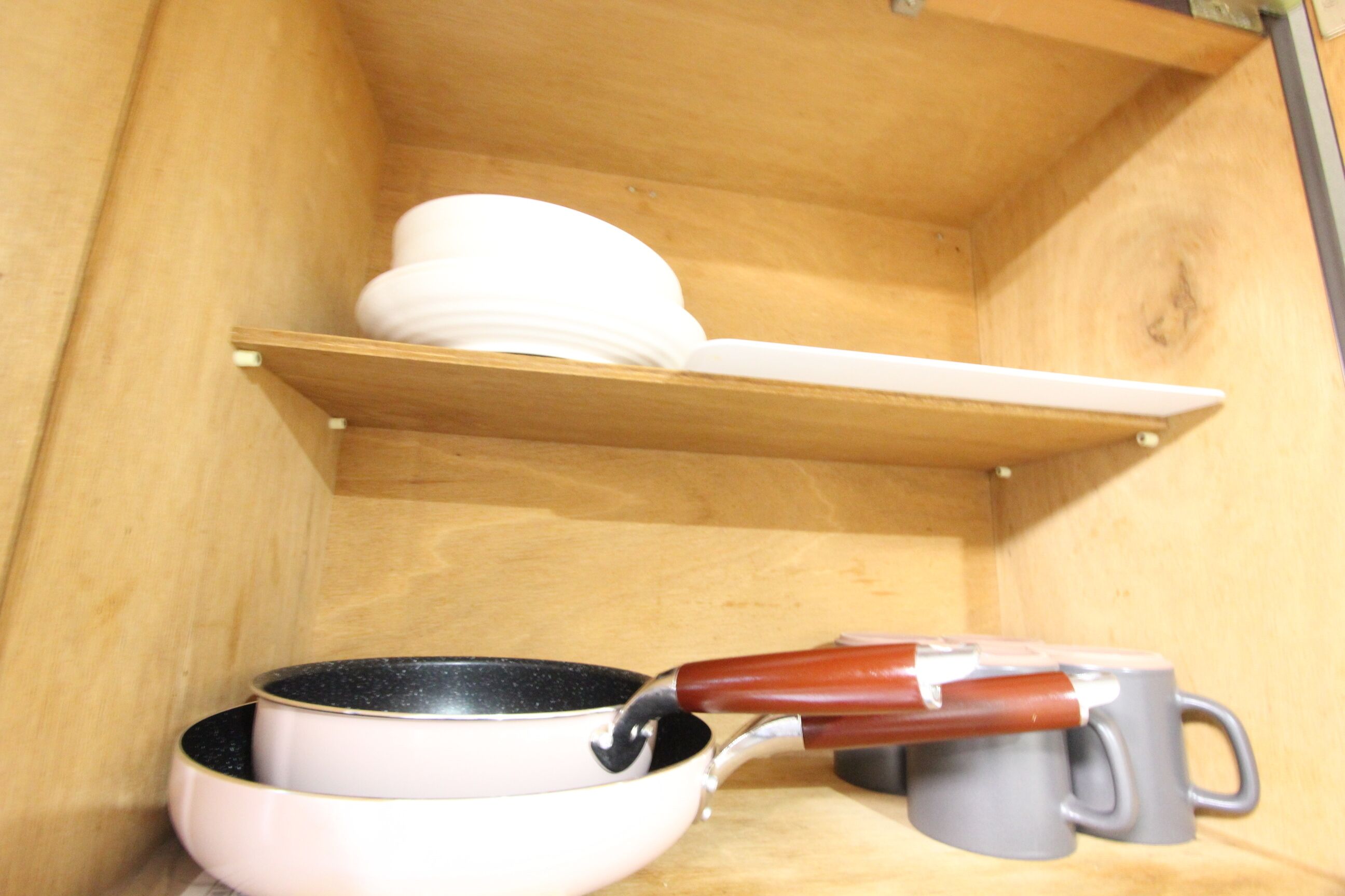 Una cocina con un estante de madera que contiene vajilla y un hervidor en la encimera.