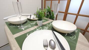 A dining table set with white plates, cutlery, and two wine glasses.