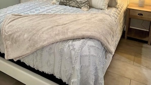 Un dormitorio con una cama, dos mesitas de noche, una ventana con cortinas y decoración en la pared.