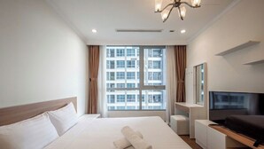 A hotel room with a large bed, a flat-screen TV, a desk, and a window with curtains. - Vinhomes Central Park (Ho Chi Minh City)