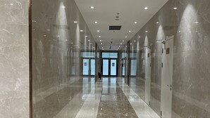 A modern hallway with marble walls and floors, leading to a glass door entrance. - Vinhomes Central Park (Ho Chi Minh City)