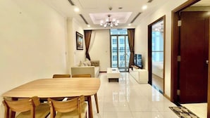 A modern living room with a dining table, sofa, and TV. - Vinhomes Central Park (Ho Chi Minh City)