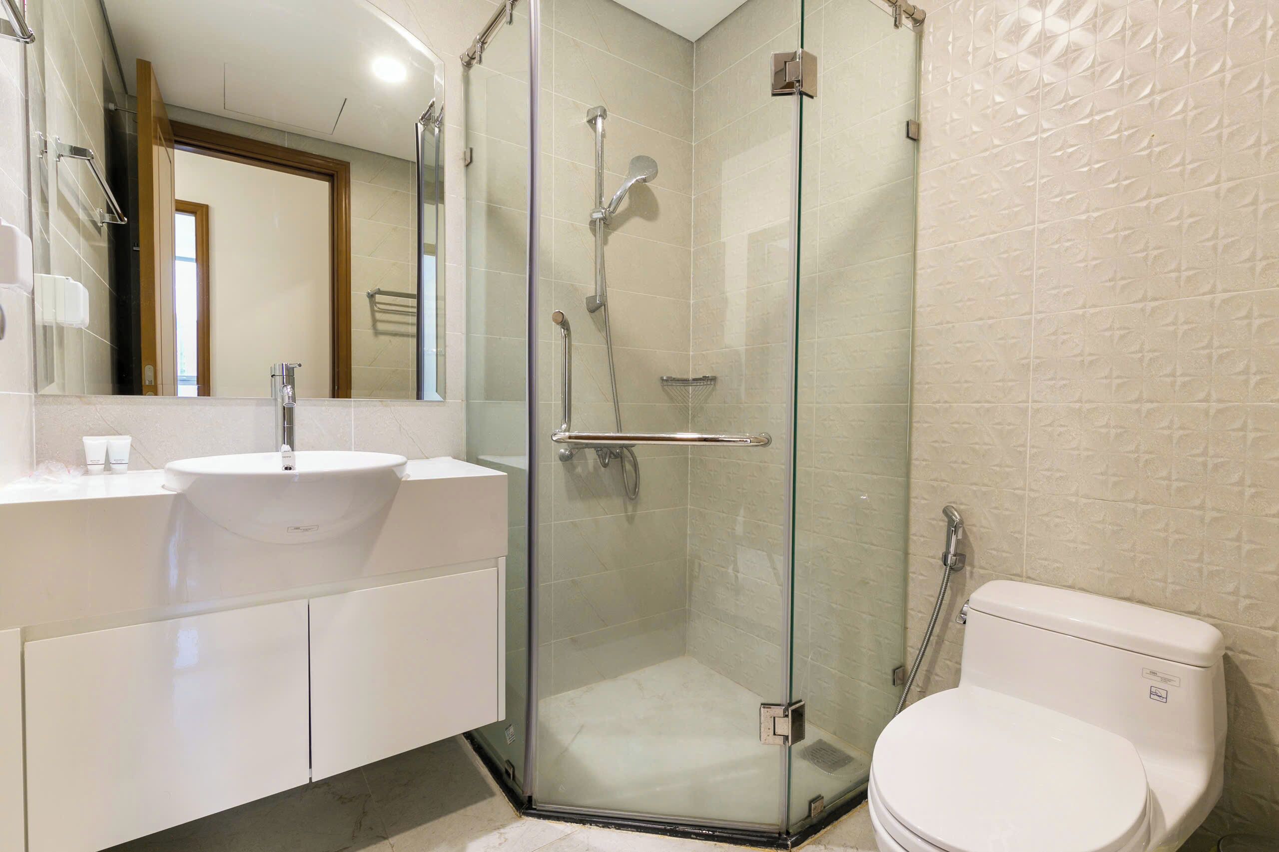 A modern bathroom with a glass-enclosed shower, a white sink, and a toilet.