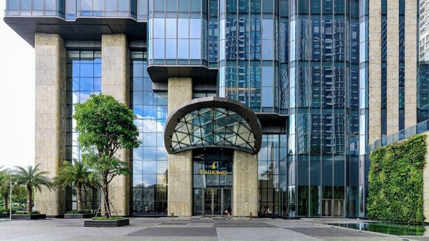 A modern building with a curved glass entrance, large pillars, and a sign reading 'VINHOMES.' - Vinhomes Central Park (Ho Chi Minh City)