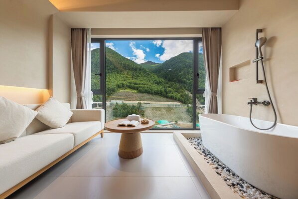 A modern bathroom with a bathtub, a sofa, and a table with books.