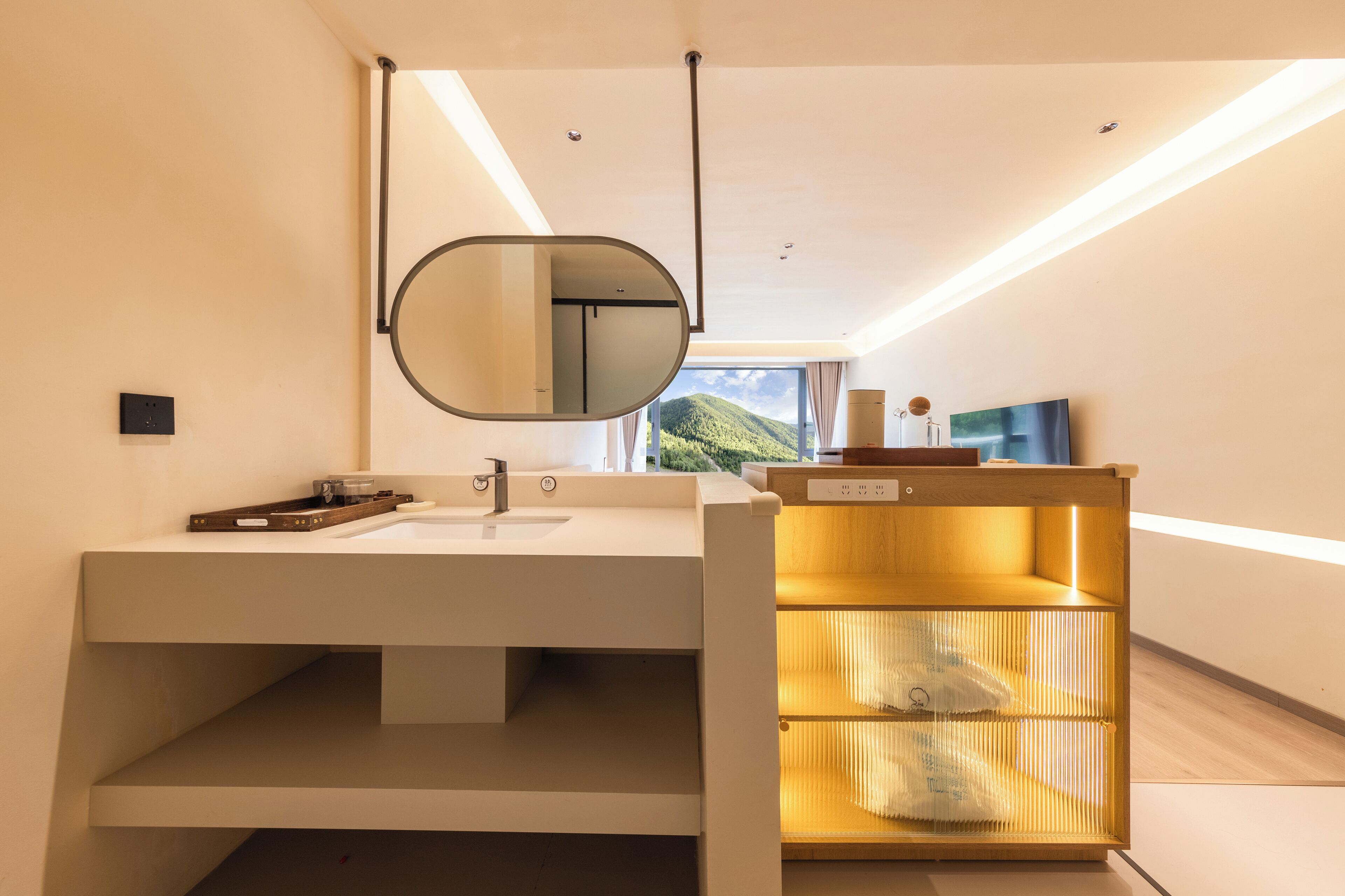 Un baño moderno con un espejo grande, un lavamanos y un estante empotrado.