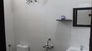 A bathroom with a toilet, a sink, and a shower. - Rams Inn (Thanjavur)