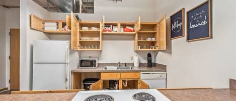 A compact kitchen with built-in appliances, wooden cabinets, and a microwave.
