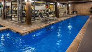 Una piscina interna con pareti in vetro, poltrone relax e attrezzature per esercizi.