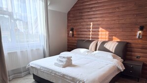 Un lit bien fait, avec des serviettes pliées, une tête de lit en bois et deux lampes fixées au mur.