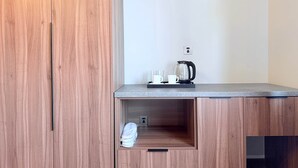 A modern kitchen with wooden cabinetry, a countertop, and a kettle.