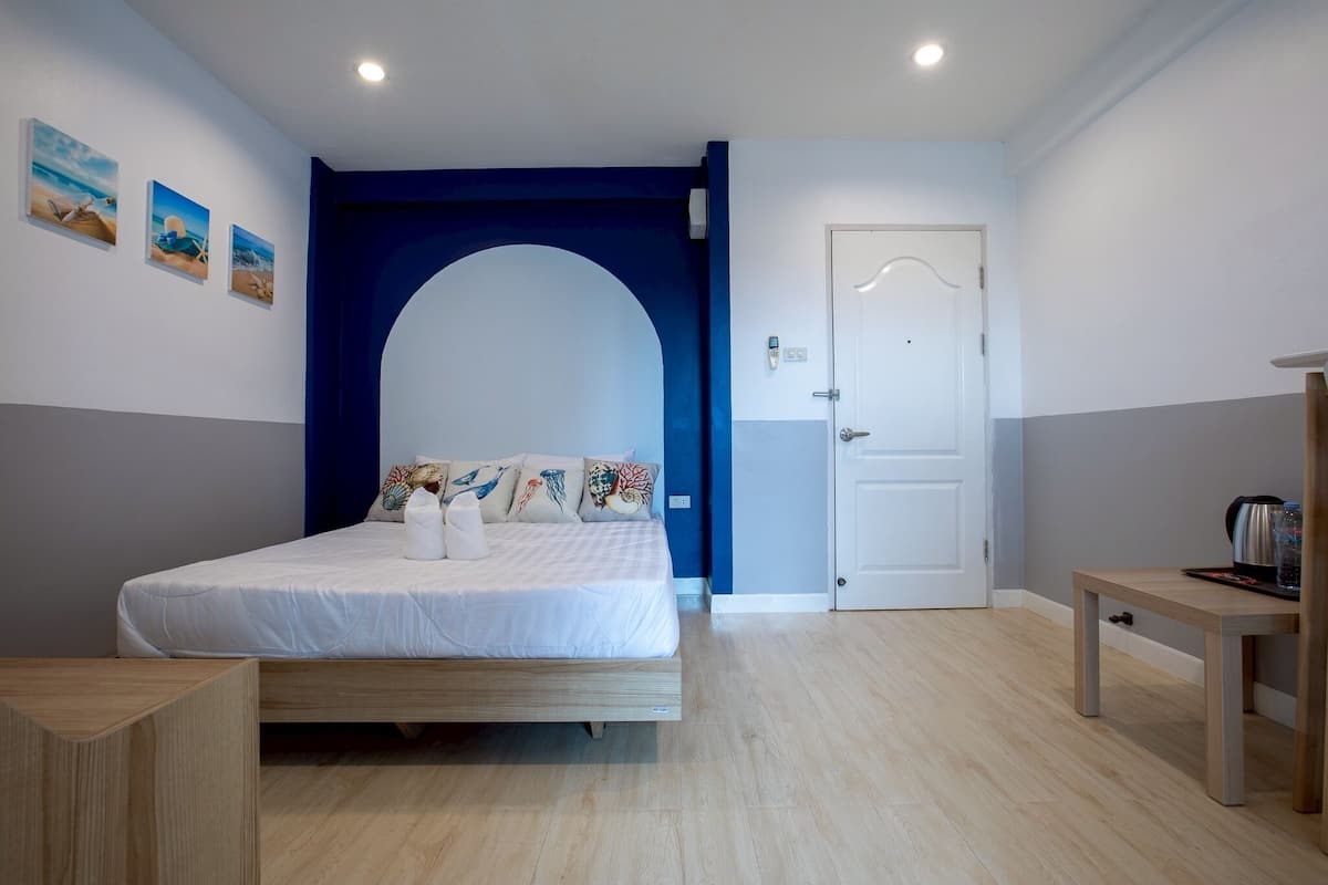 Une chambre à coucher avec un lit, une table en bois, une porte blanche et un arc bleu.