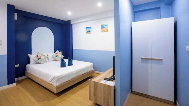 A bedroom with a bed, a desk, a wardrobe, and two small wall art pieces. - PanoSea Bangsaen (Chonburi)