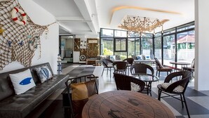 A modern interior with a checkered floor, leather sofa, wicker chairs, and a round table. - PanoSea Bangsaen (Chonburi)