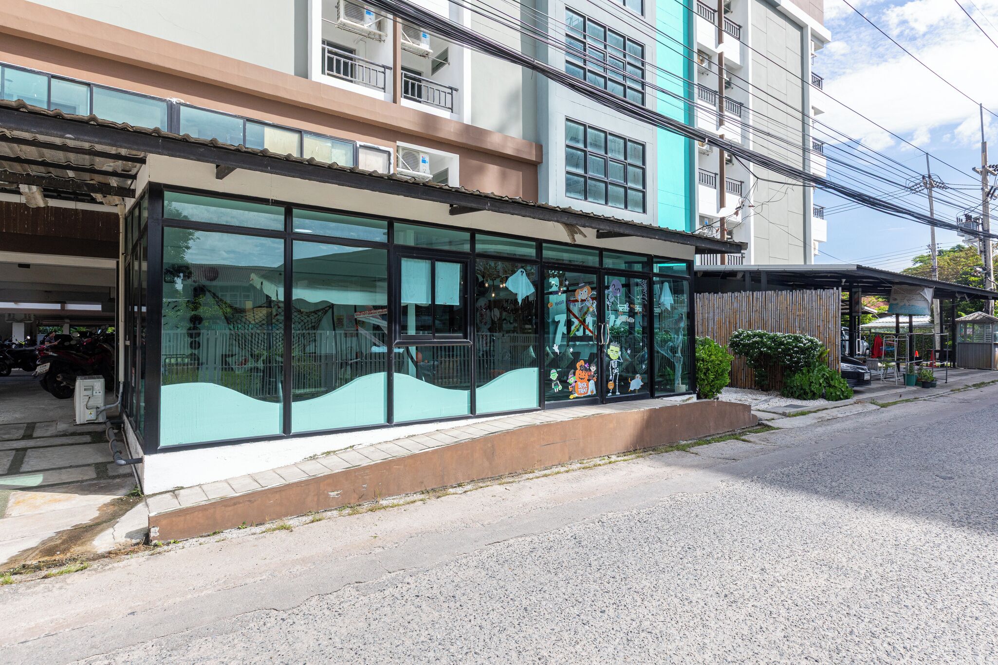 A modern building with large glass windows, a covered entrance, and a parking area.