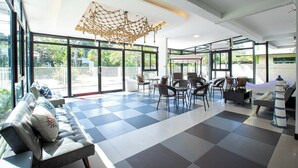 A spacious indoor area with large windows, a checkered floor, and a netted ceiling light fixture. - PanoSea Bangsaen (Chonburi)