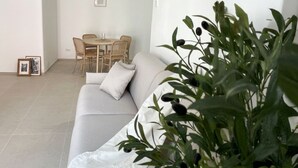 Uma sala de estar moderna com um sofá, uma mesa de jantar com cadeiras e um vaso de planta.