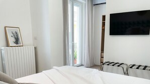 Quarto de hotel com cama, radiador, televisão e vista para o exterior.