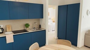 Uma cozinha moderna com armários azuis, uma pia e um espaço de refeições com uma mesa redonda e cadeiras.