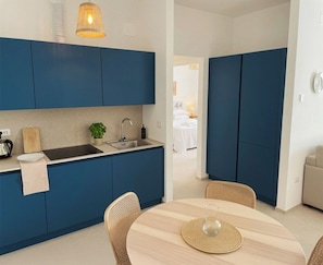 Una cocina moderna con armarios azules, un fregadero y una zona de comedor con una mesa redonda y sillas.