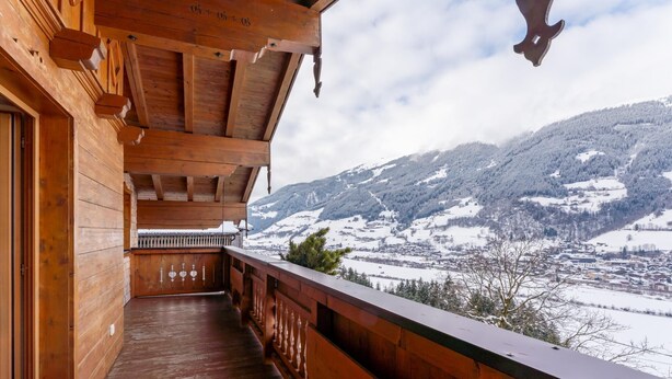 A wooden balcony with a view of snow-covered mountains. - Detached holiday home with terrace and balcony. (Bramberg am Wildkogel)