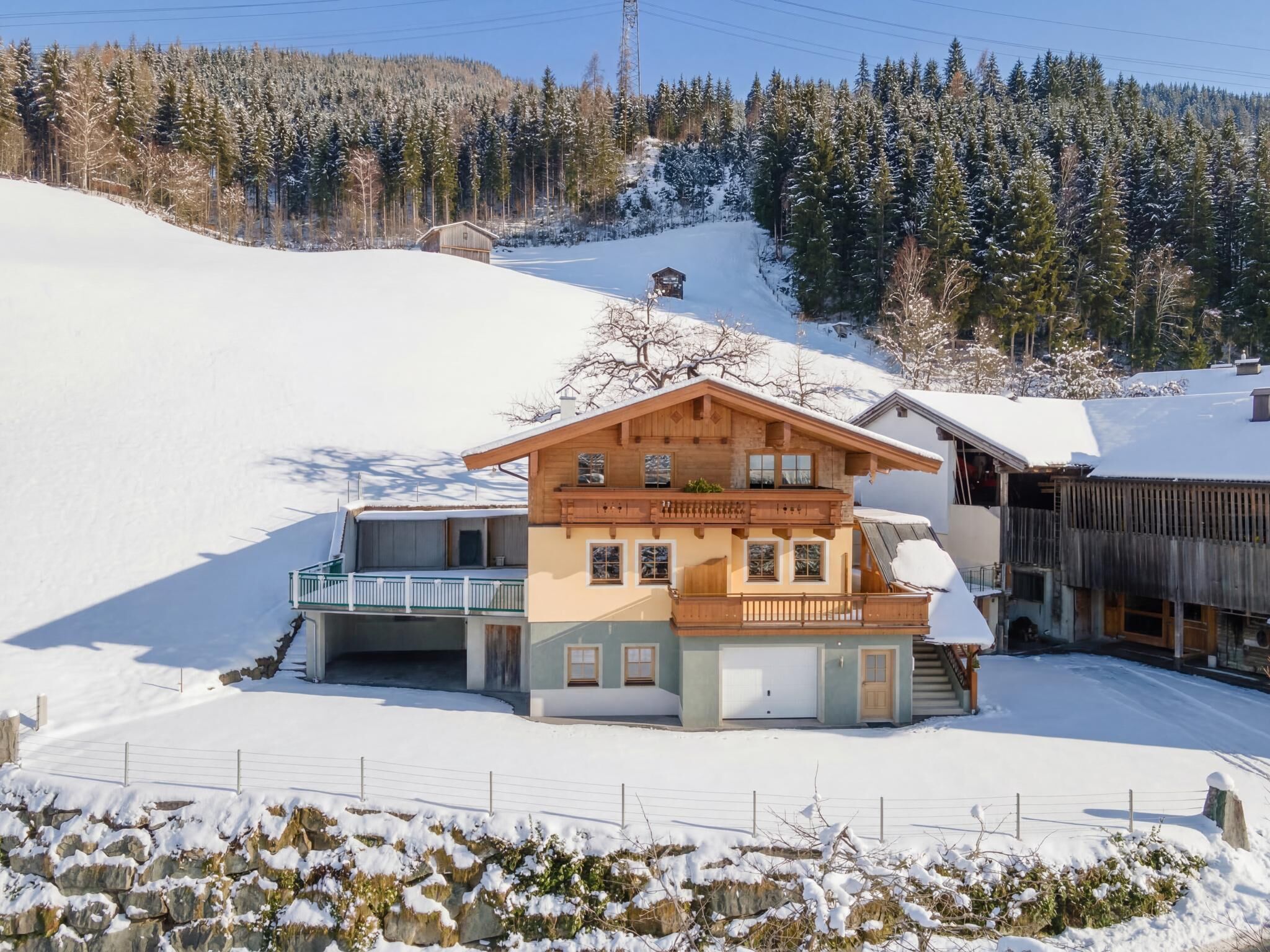 Ein Chalet mit Balkon, Garage und einer Holzterrasse.