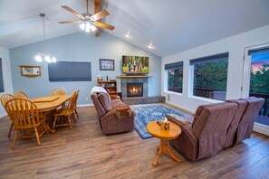A living room with a fireplace, wooden furniture, and large windows.