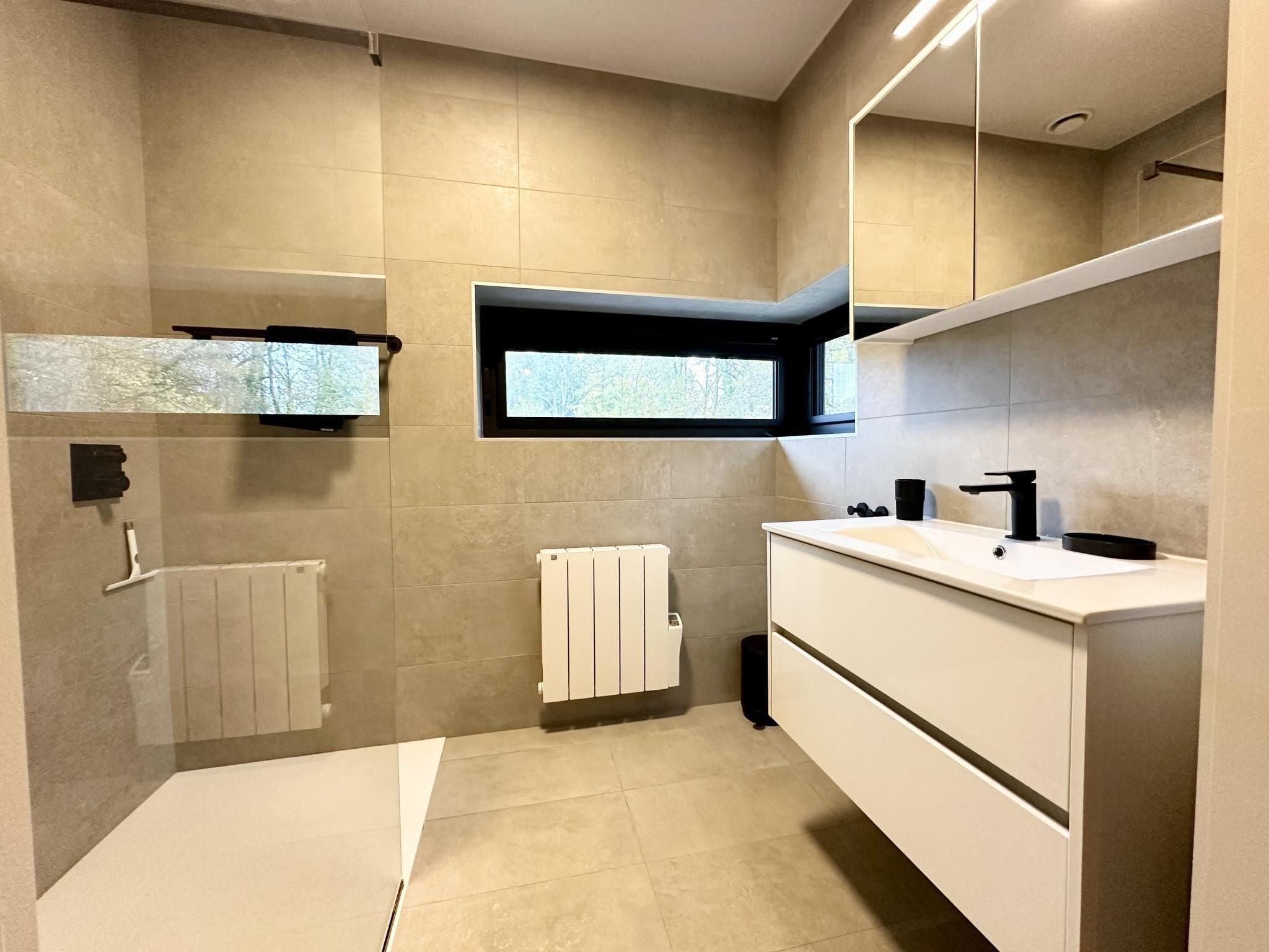 A modern bathroom with a bathtub, a sink, and a window.