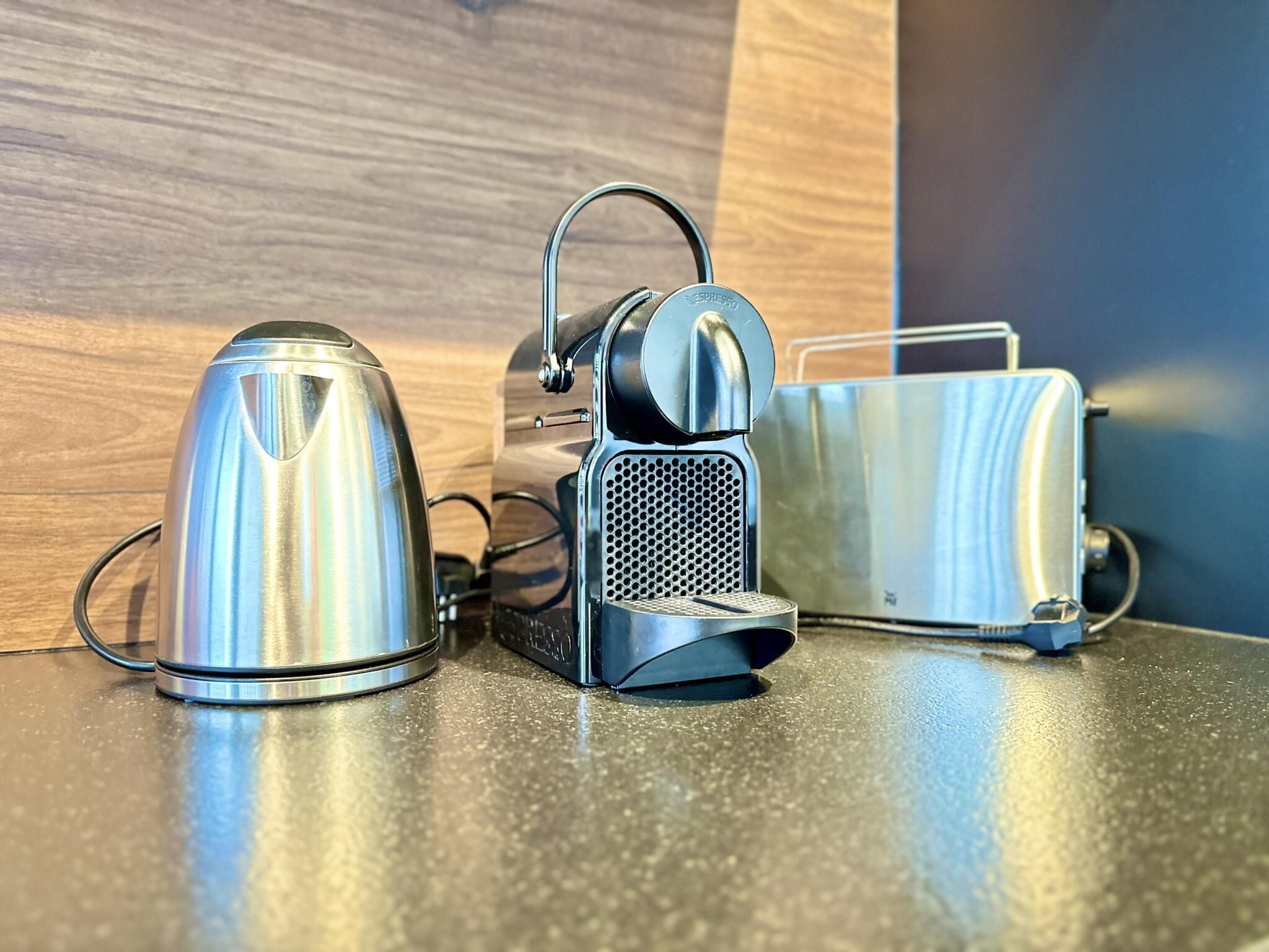 A kitchen with a kettle, a coffee maker, and a toaster on a countertop.