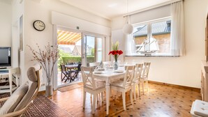 A dining area with a table set for four, a clock on the wall, and a window with a sailboat view. - Cosy coastal villa in the heart of Koksijde (Koksijde)