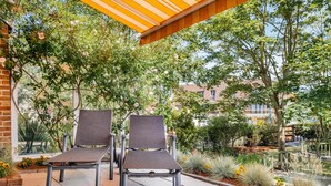 Two lounge chairs under a pergola with a view of a garden and buildings in the background. - Cosy coastal villa in the heart of Koksijde (Koksijde)