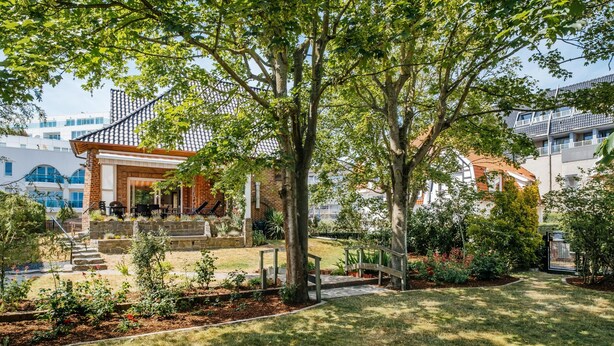 A residential garden with a brick patio, a wooden deck, and a variety of plants and flowers. - Cosy coastal villa in the heart of Koksijde (Koksijde)