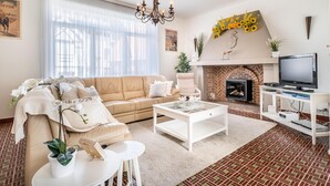 A living room with a beige sofa, white coffee table, and a fireplace with a brick design. - Cosy coastal villa in the heart of Koksijde (Koksijde)