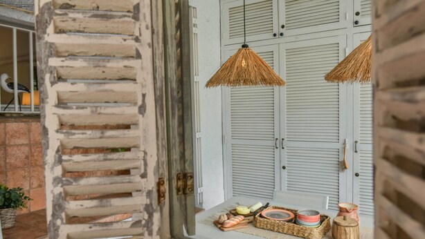 Una habitación con una puerta de madera rústica, una ventana con vistas y una pequeña mesa con adornos.