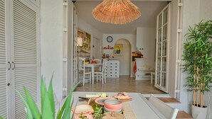 Una cocina de concepto abierto con zona de comedor, una lámpara colgante de ratán y una planta en maceta.