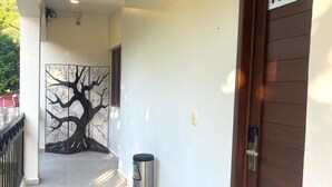 Ein Flur mit einer Tür, auf der „101“ steht, einem Mülleimer und einer an der Wand befestigten Überwachungskamera.