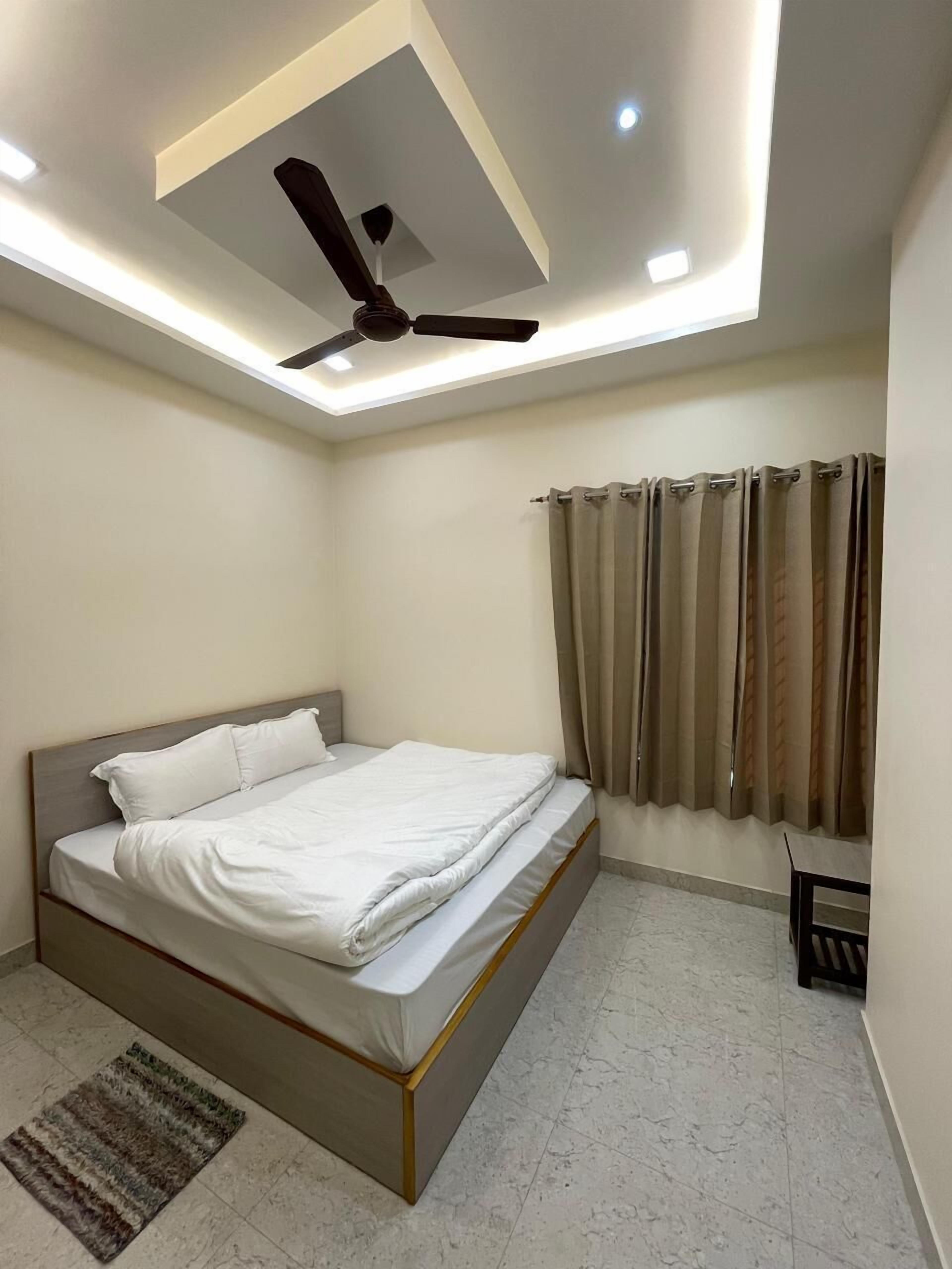 A modern bedroom with a bed, ceiling fan, and curtains.