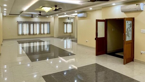 A spacious, well-lit hotel lobby with a polished marble floor, ceiling fans, recessed lighting, and an air conditioning unit. - Royal Celebration (Lucknow)