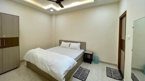 A bedroom with a bed, a wardrobe, a ceiling fan, and a door. - Royal Celebration (Lucknow)