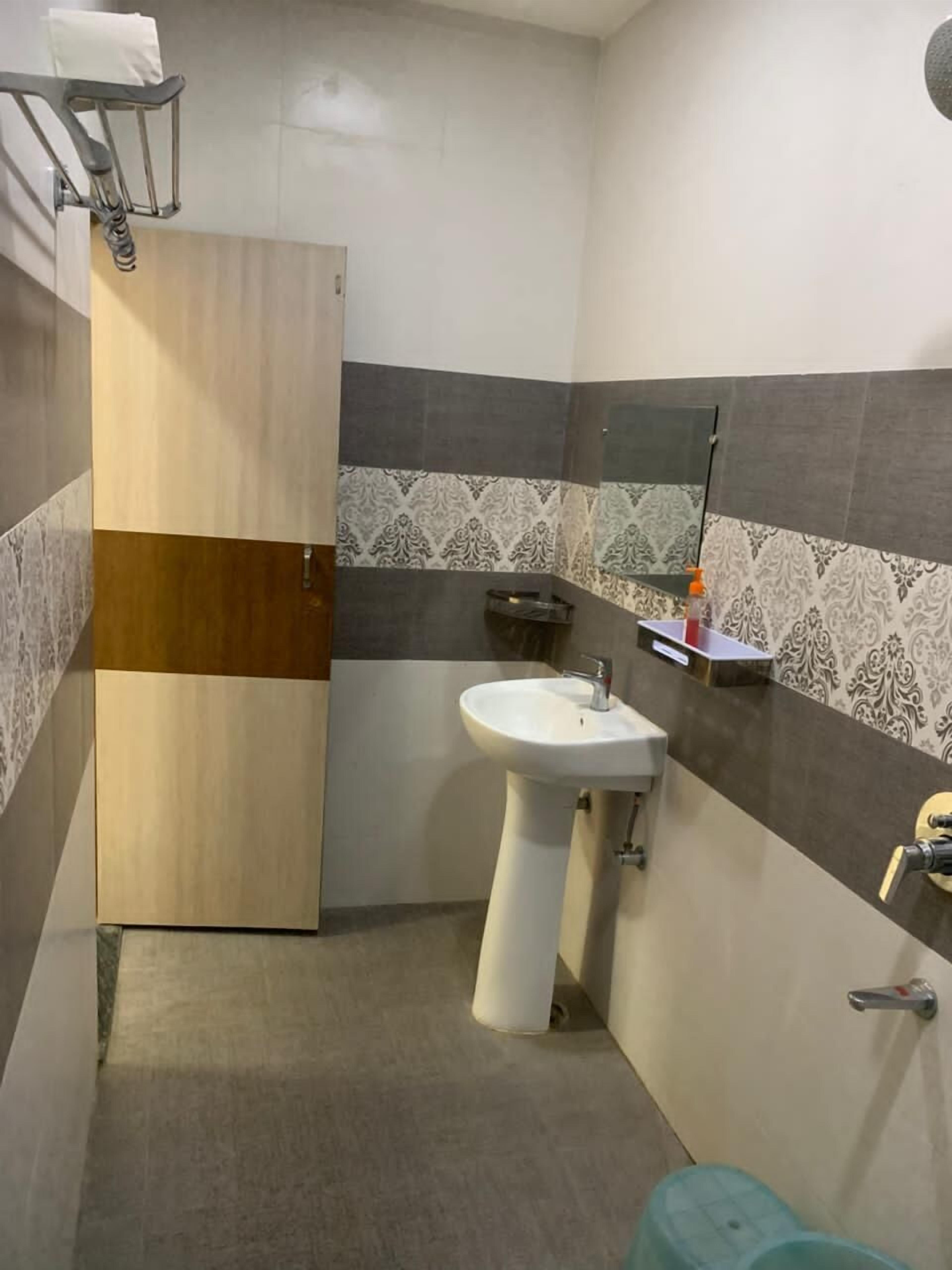 A bathroom with a wooden door, a white sink, a mirror, and patterned tiles.
