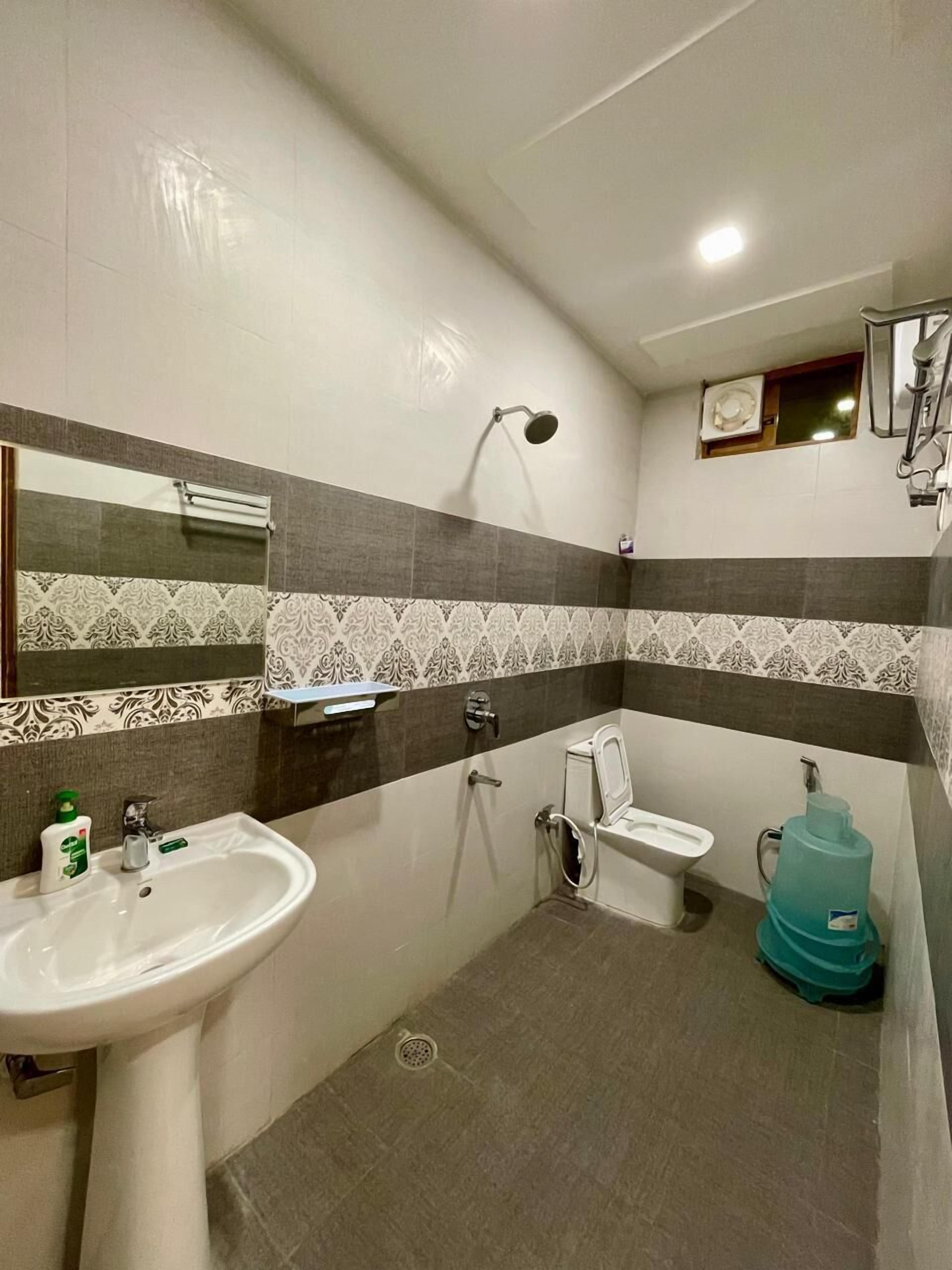 A bathroom with a sink, toilet, shower, and a large water dispenser.