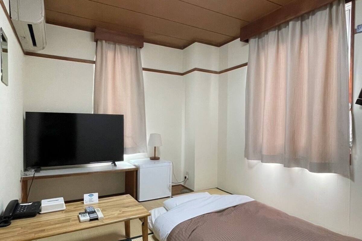 Een hotelkamer met een bed, een bureau met een televisie, een klein tafeltje en een stoel.