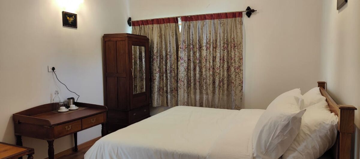 A bedroom with a bed, a wooden dresser, a nightstand, and a mirror.