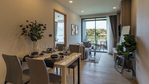 Un coin repas avec une table dressée pour quatre personnes, une plante en pot et une vue sur l’extérieur.