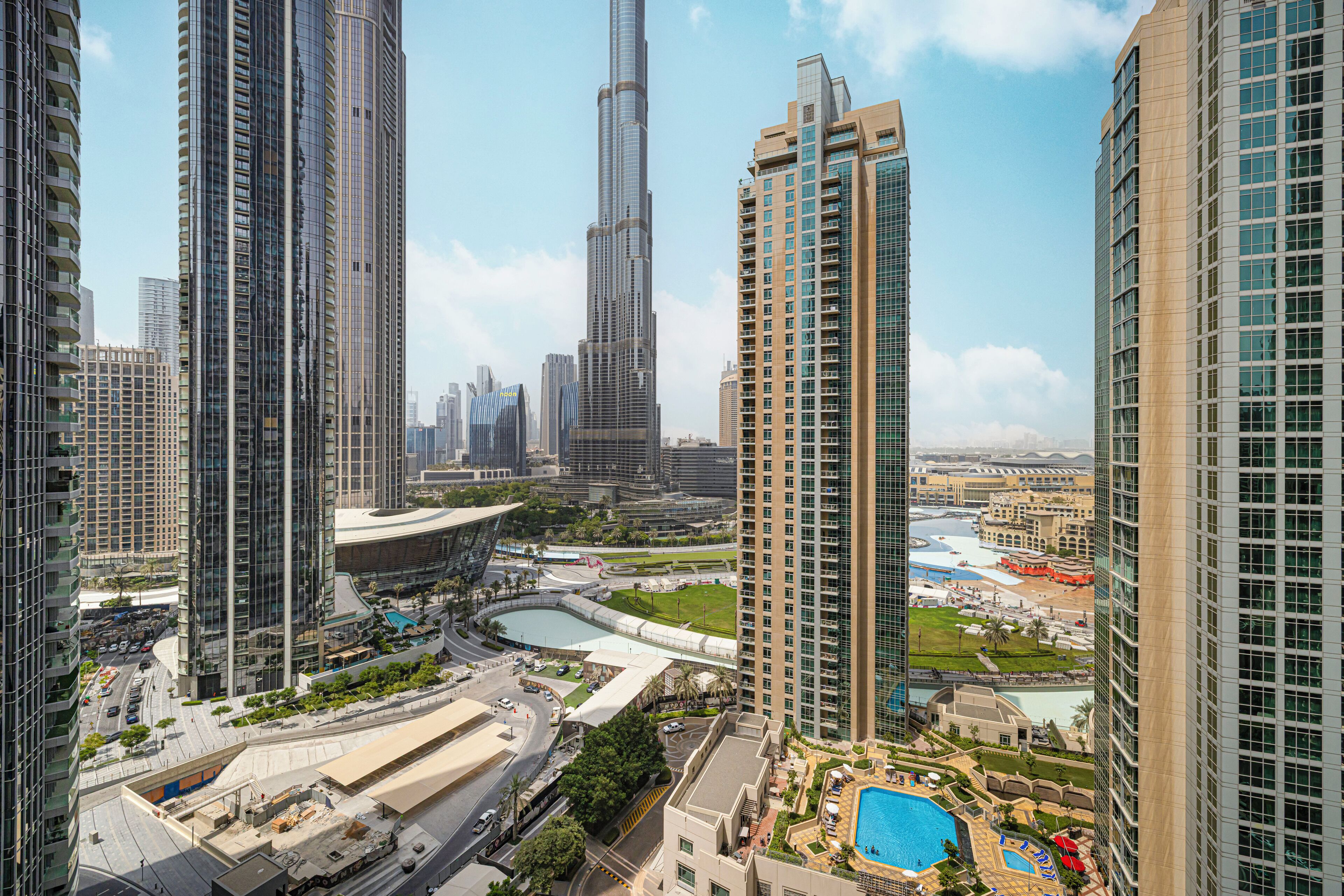 A high-rise building with a pool and a view of the surrounding cityscape.