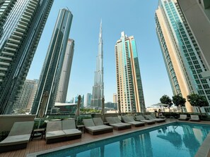 A rooftop pool area with lounge chairs and a view of tall skyscrapers. - Act 1 Act 2 Towers by DVH Luxe Retreats (Dubai)