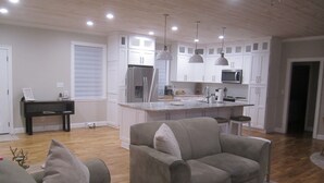 A modern kitchen with white cabinets, a stainless steel refrigerator, and pendant lighting.