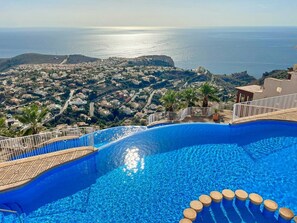 Una piscina con vistas a un pueblo costero y al mar.